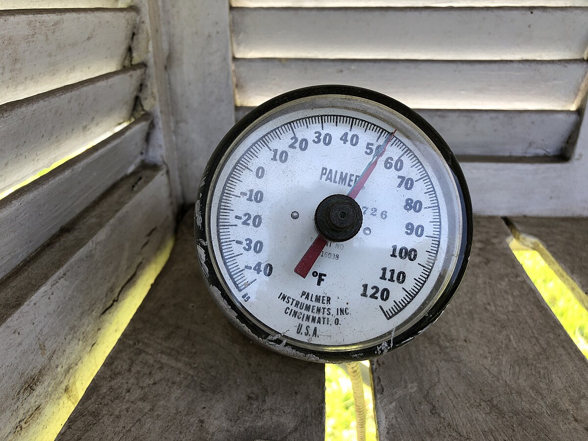 A soil thermometer showing temperature readings, used for checking soil temperature before fertilizing a lawn